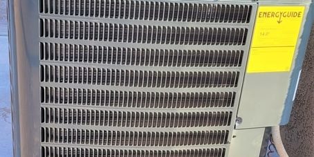 Outdoor air conditioner with yellow sticker on heat pump.