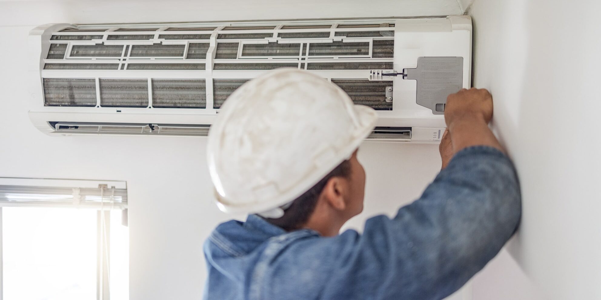 A man installing an air conditioner in a room.