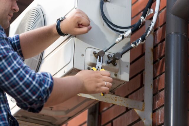 A person using pliers to fix a air conditioner. A person using pliers to fix a air conditioner.