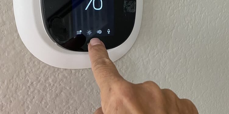 A hand pressing a thermostat.