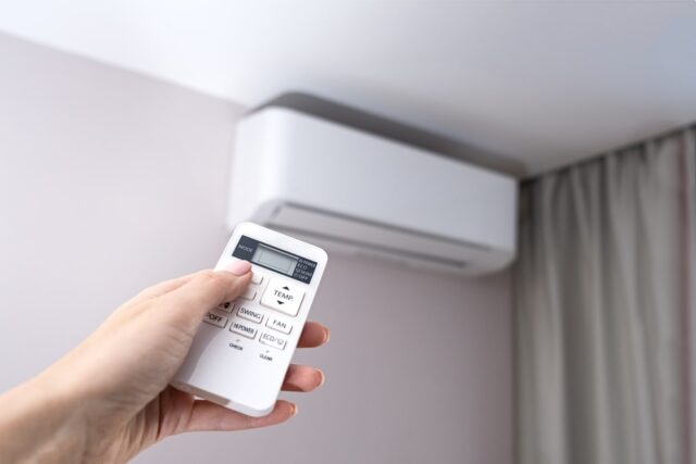 A person holding a remote control to an air conditioner. A person holding a remote control to an air conditioner.