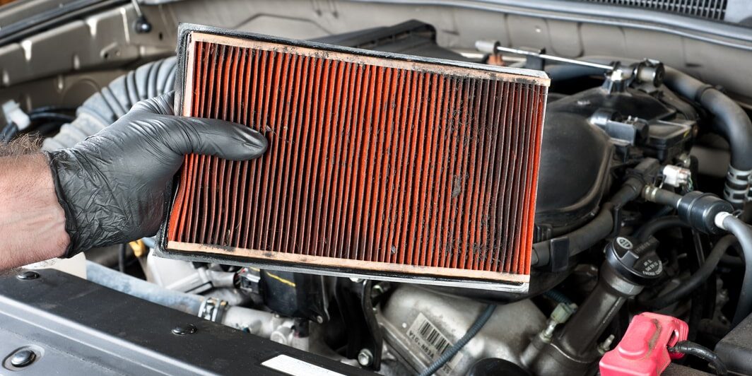 A person is holding an air filter in a car.