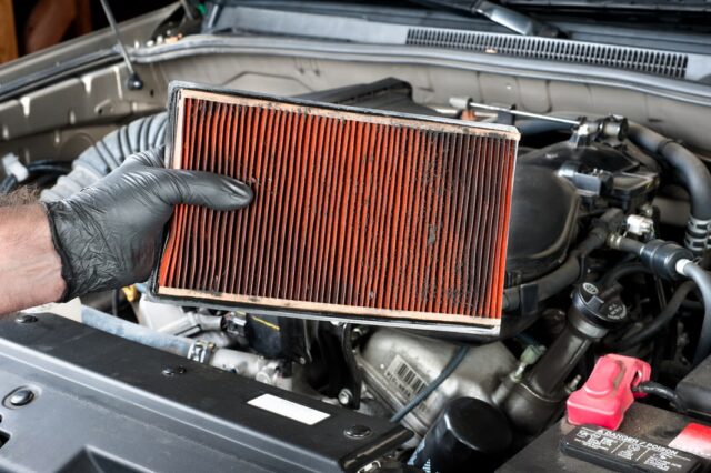 A person is holding an air filter in a car. A person is holding an air filter in a car.