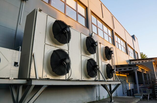 A group of industrial air conditioners on the side of a building. A group of industrial air conditioners on the side of a building.