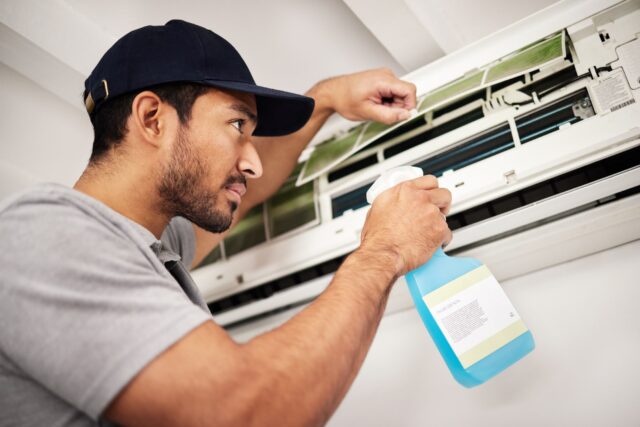 A man cleaning an air conditioner. A man cleaning an air conditioner.