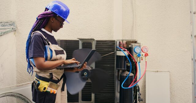 A woman working on a laptop in front of an air conditioner. A woman working on a laptop in front of an air conditioner.